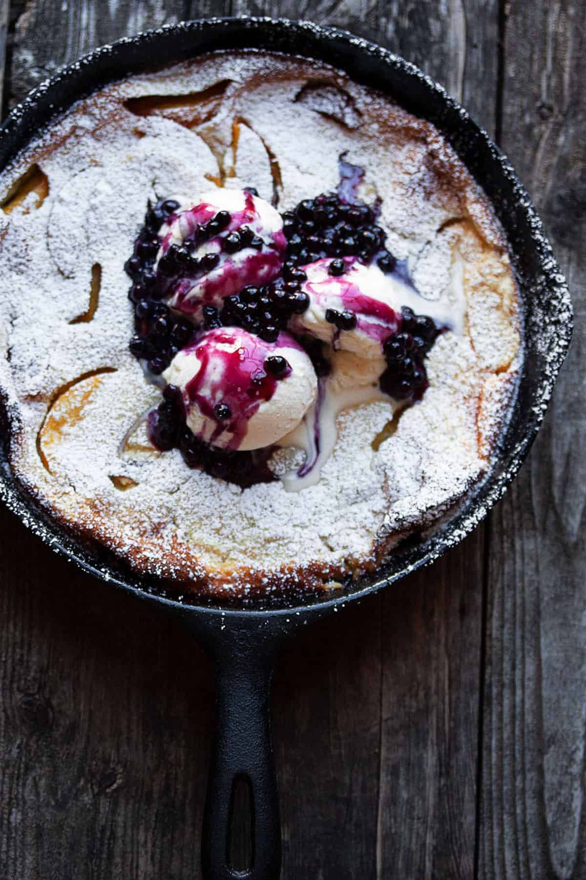 peach Dutch baby with blueberry sauce in cast iron skillet