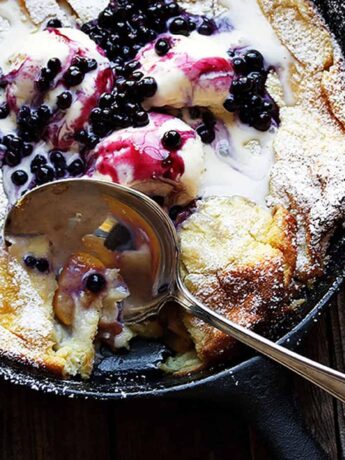 peach Dutch baby with blueberry sauce in cast iron skillet