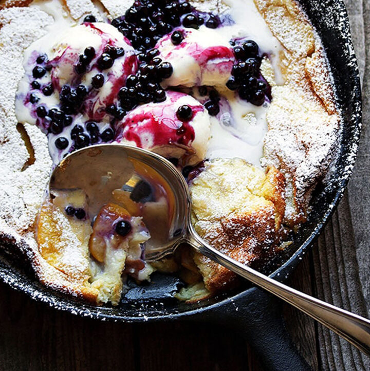 peach Dutch baby with blueberry sauce in cast iron skillet