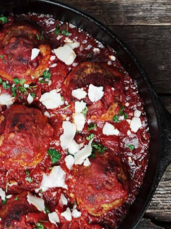 baked meatballs and tomato sauce in cast iron skillet