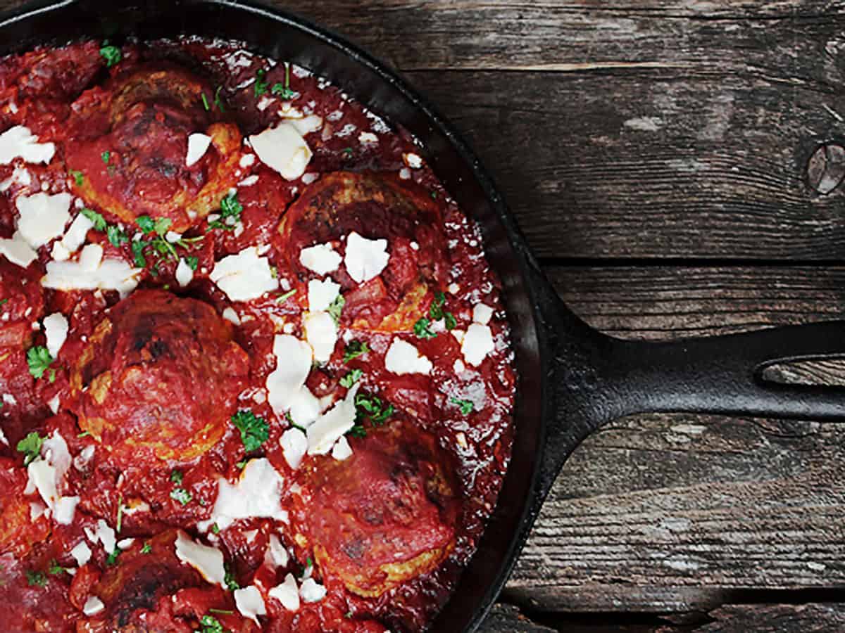 baked meatballs and tomato sauce in cast iron skillet