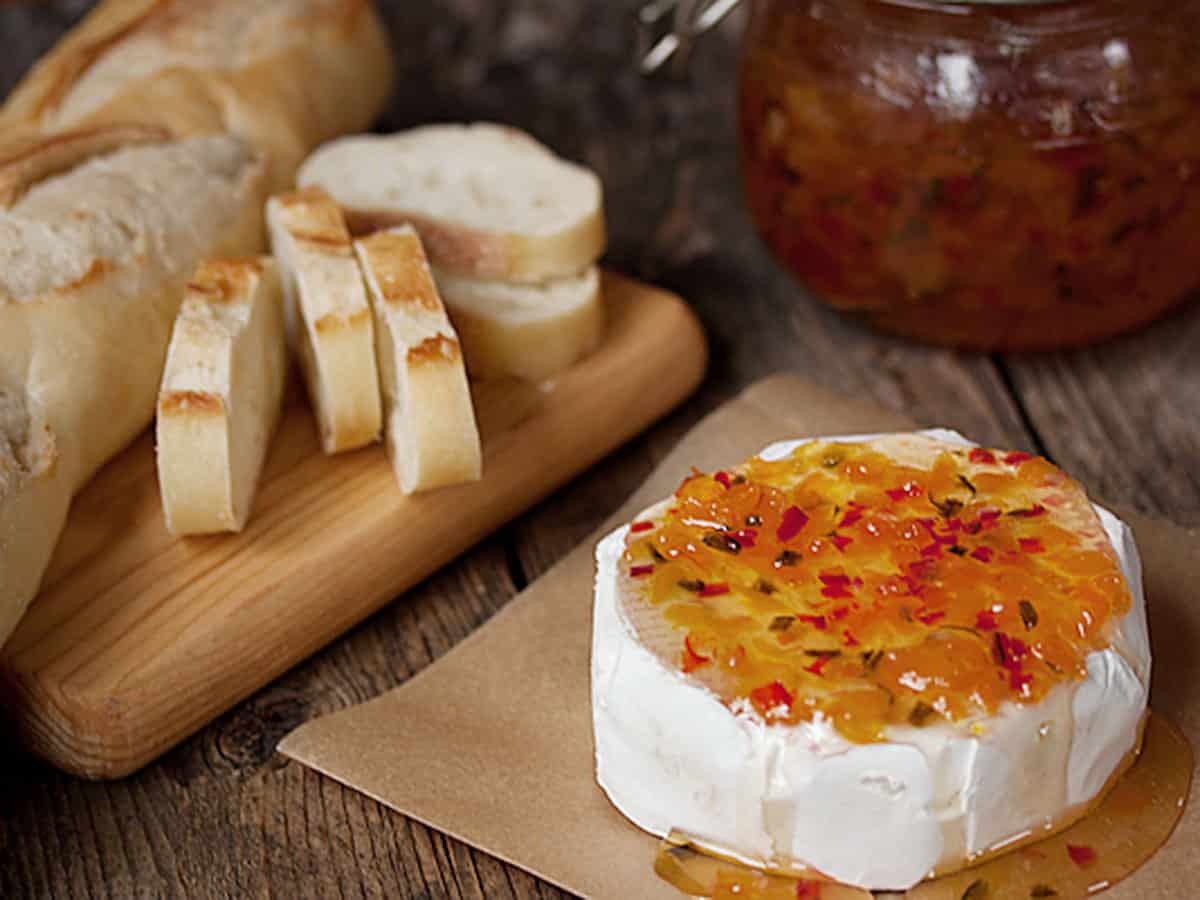 apricot jalapeno cheese topper on a round of brie with bread slices