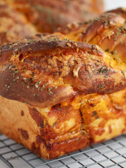 Homemade cheese bread on a cooling rack.