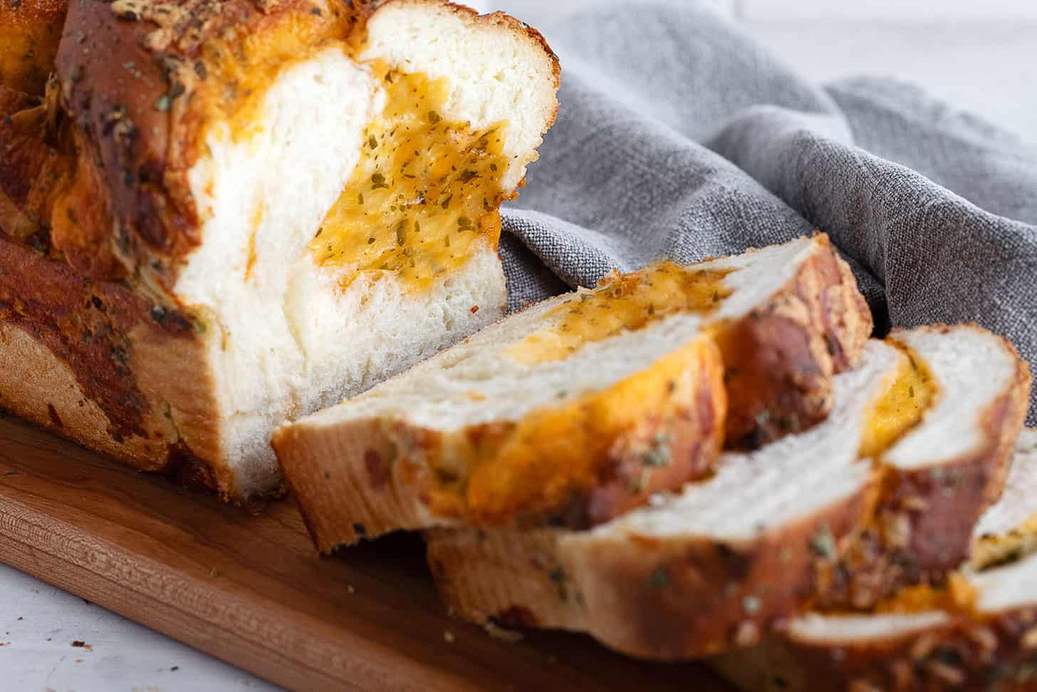 Homemade cheese bread sliced on a bread board.