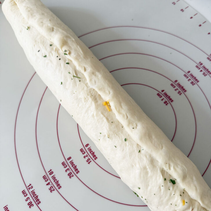 Pinching the seam of the rolled dough together.