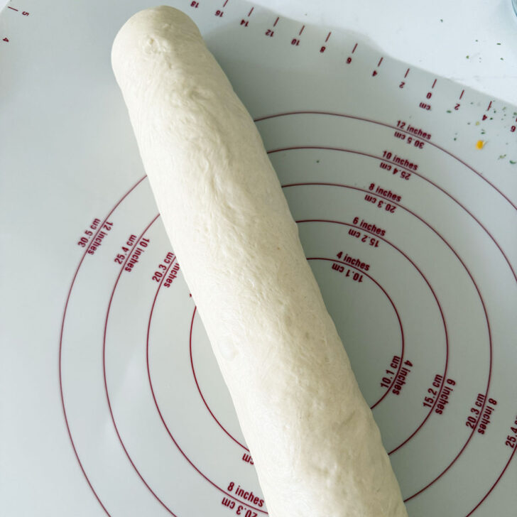Filled dough log on a baking mat.