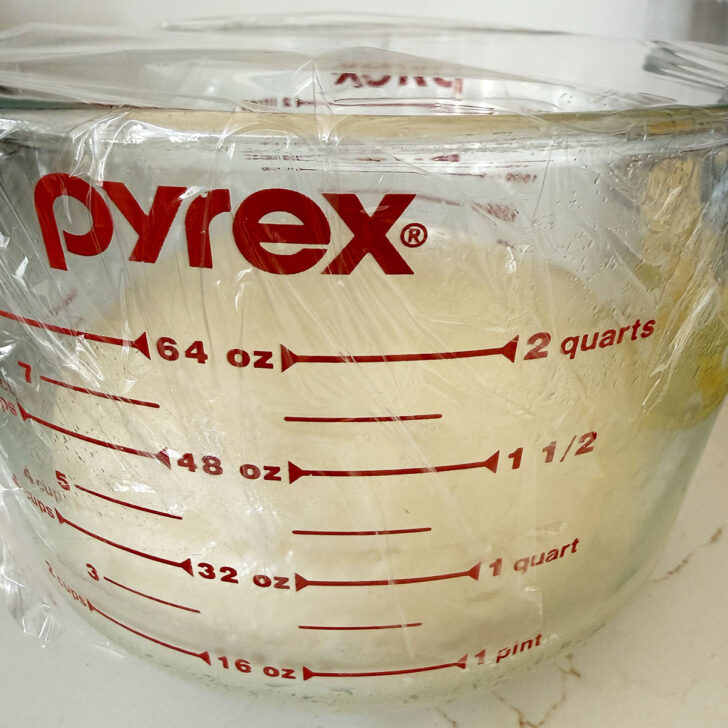 Dough set to rise in a large measuring cup.