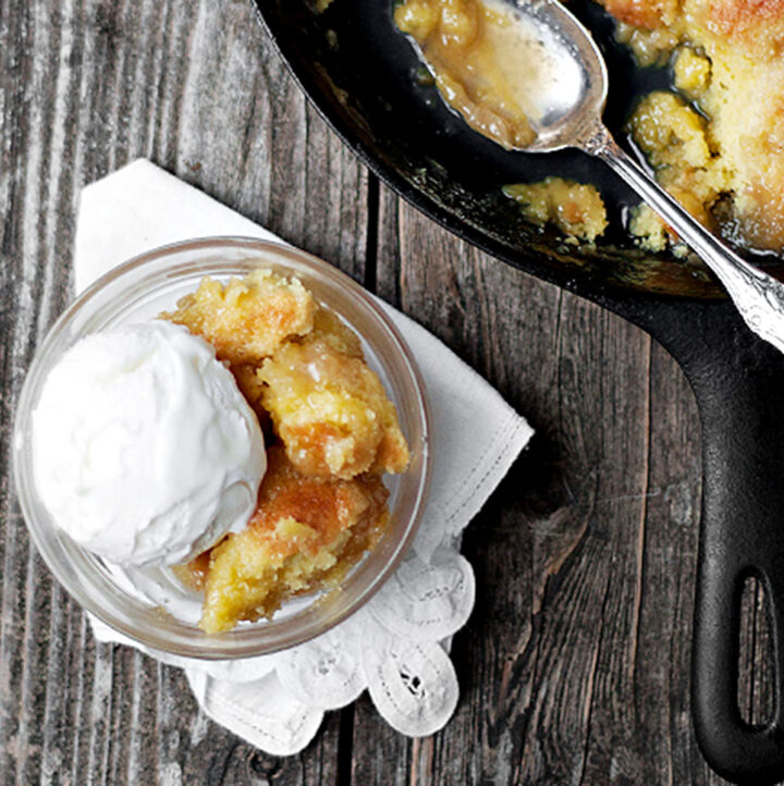 maple syrup pudding cake in cast iron skillet with some in bowl with ice cream