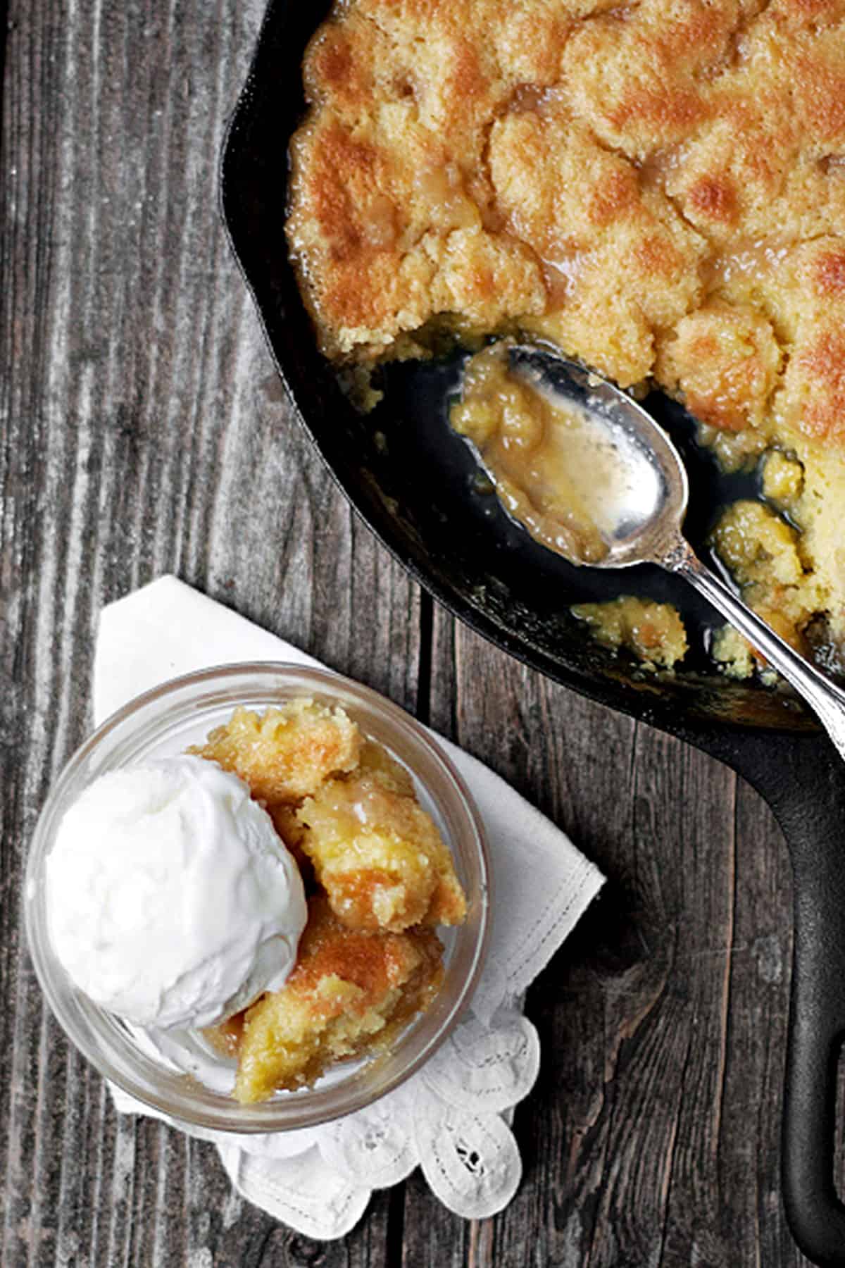 maple syrup pudding cake in cast iron skillet with some in bowl with ice cream