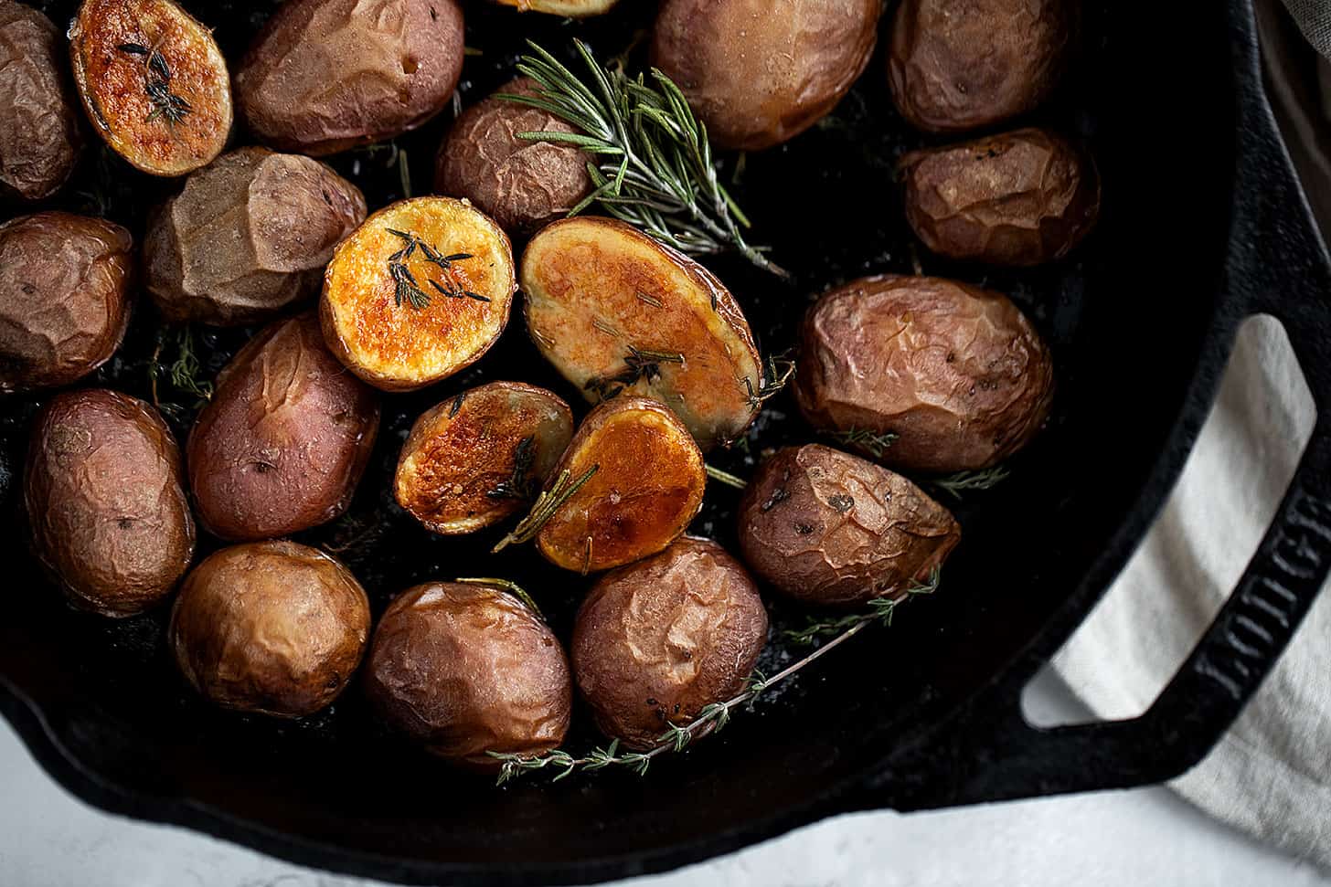crispy skillet baby potatoes in cast iron skillet with rosemary