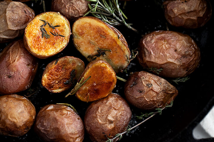 crispy skillet baby potatoes in cast iron skillet with rosemary