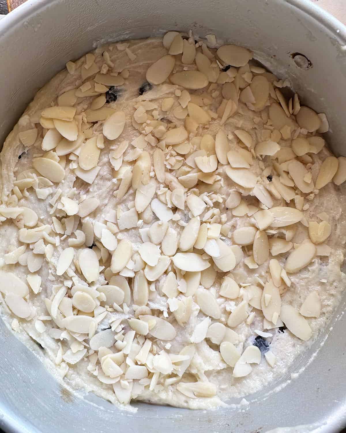 batter in pan with almonds scattered on top