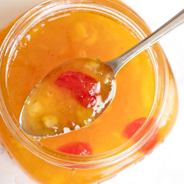 peach marmalade in spoon on top of jar