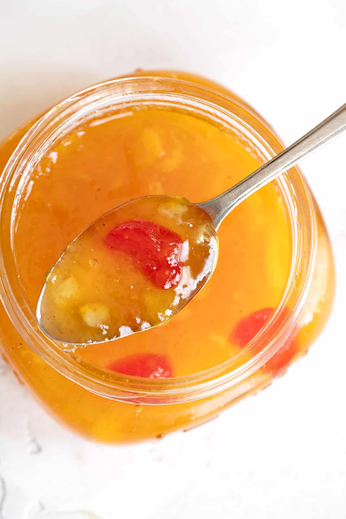 peach marmalade in spoon on top of jar