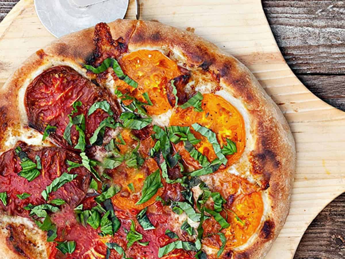heirloom tomato pizza sliced on peel