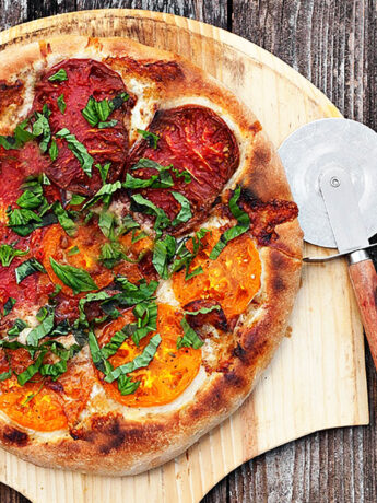 heirloom tomato pizza on pizza peel with pizza cutter