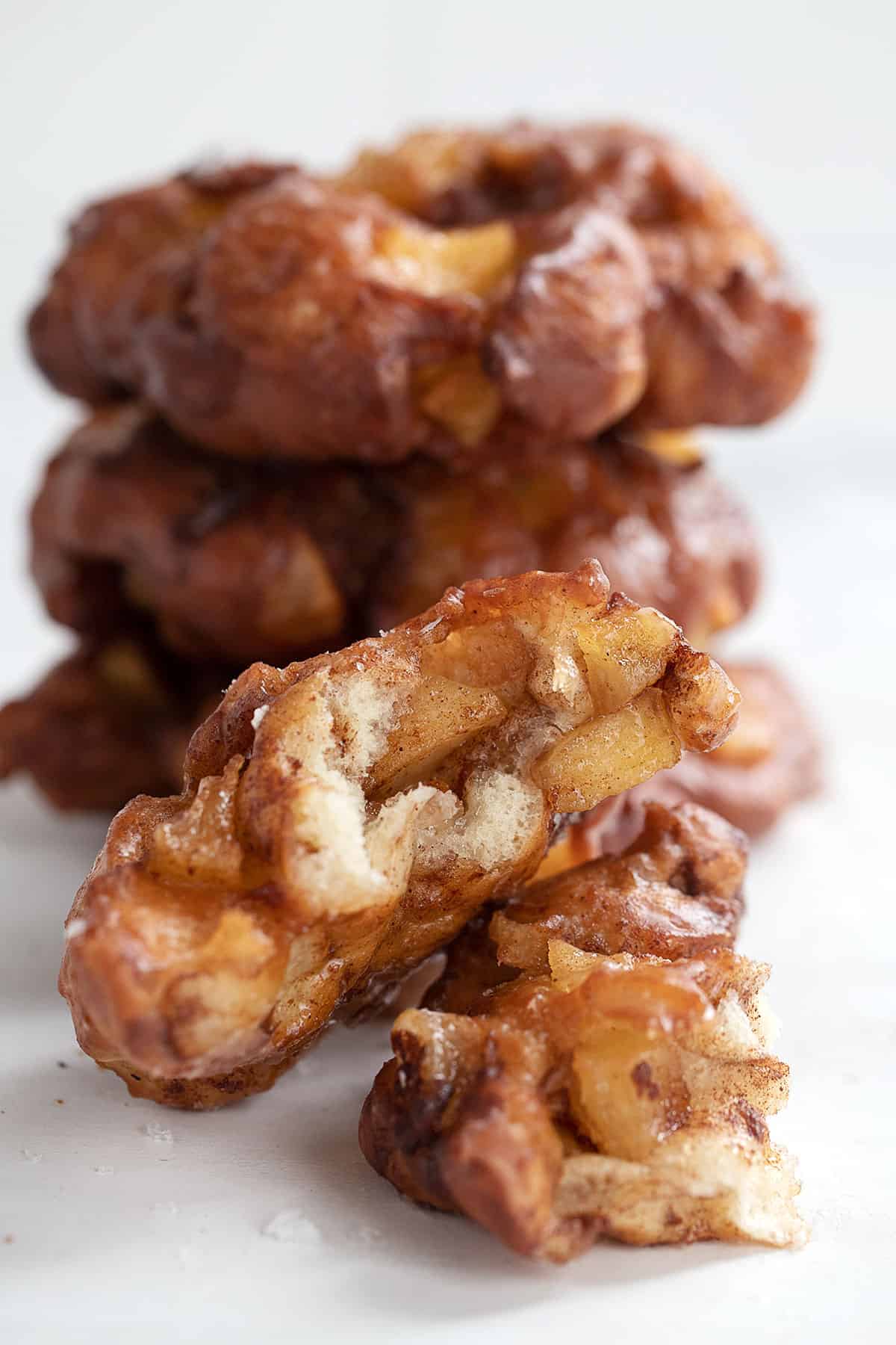 apple fritter yeast doughnuts stacked with one broken open