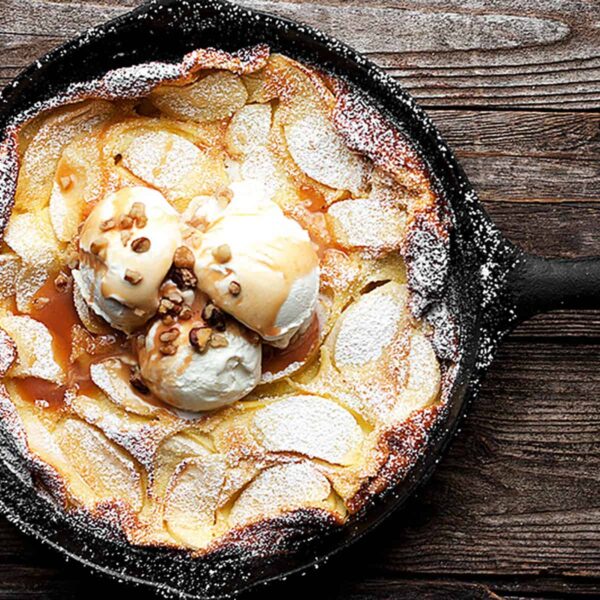 Dutch baby with apples and caramel sauce in cast iron skillet
