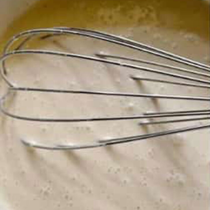Cream and egg mixture mixed up in a bowl.