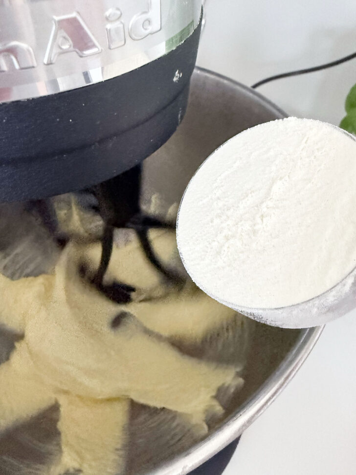 Adding flour to the batter in the mixing bowl.