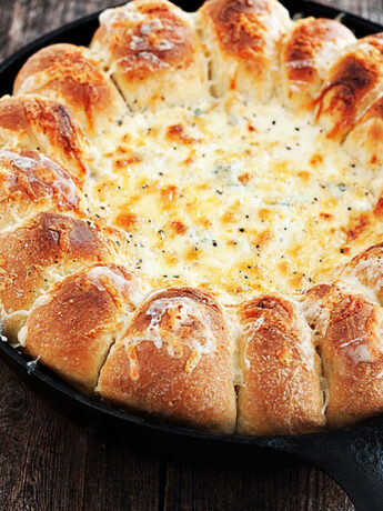 spinach artichoke dip with bread rolls in skillet