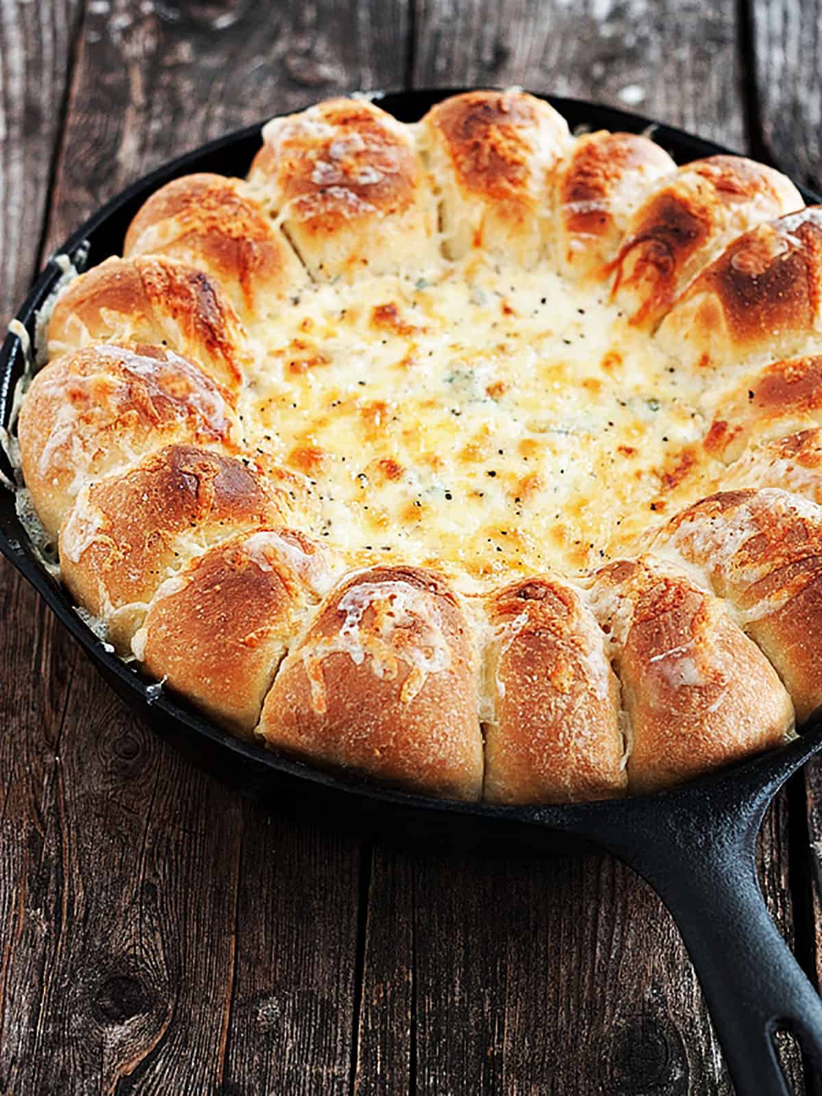 spinach artichoke dip with bread rolls in skillet