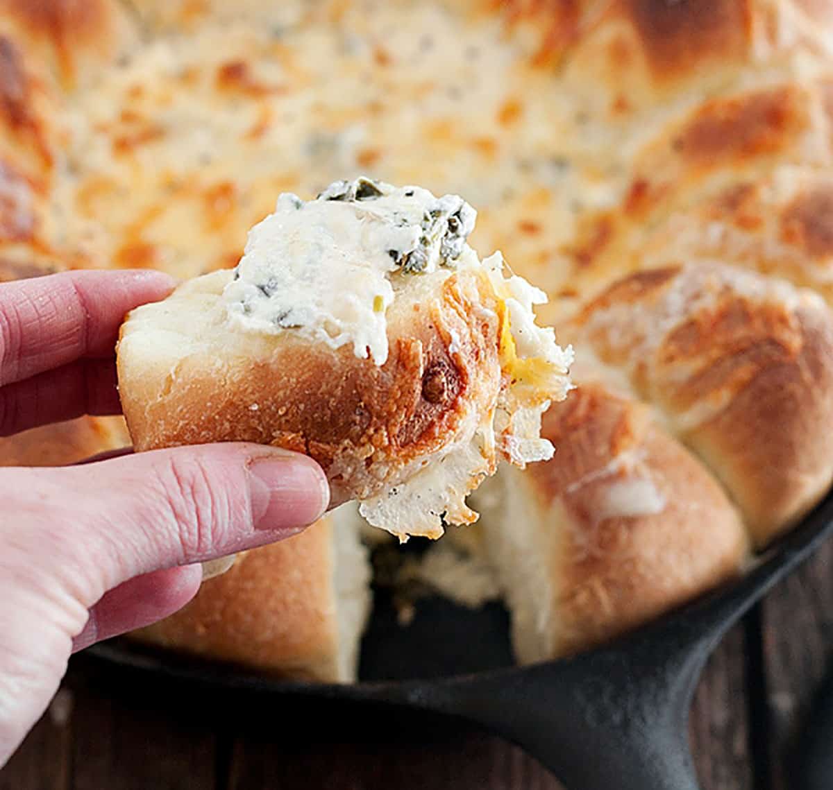 spinach artichoke dip with bread rolls in skillet