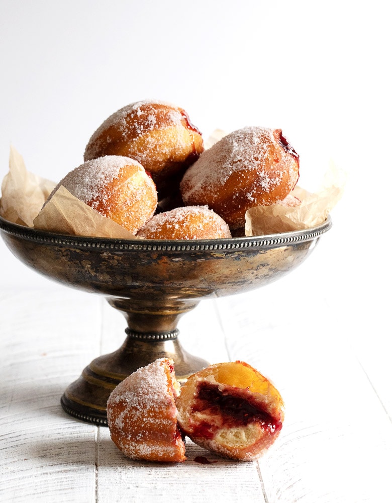 jam-filled paczki in a silver bowl and cut open