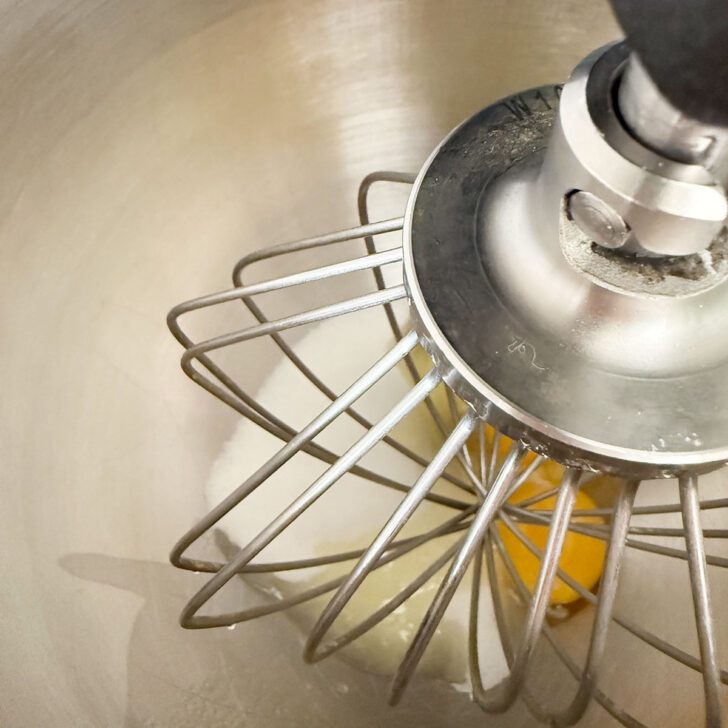 Eggs and sugar in the bowl of a stand mixer with the whisk attachment.