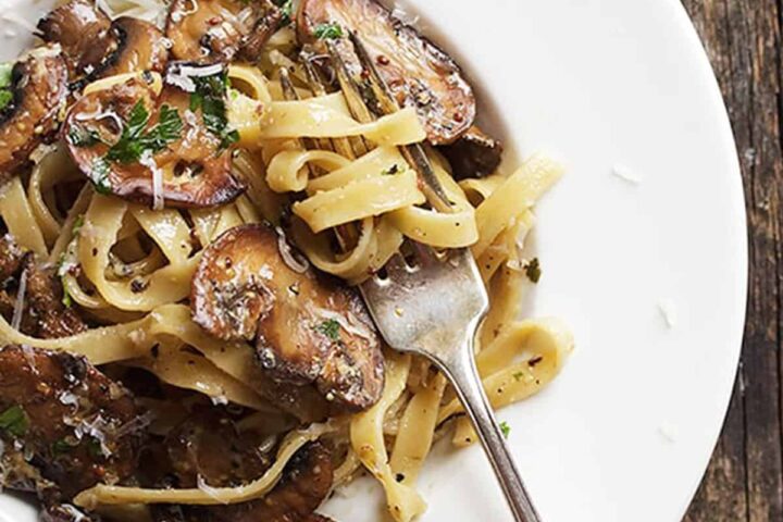 pasta with mushrooms and mustard sauce in bowl with fork
