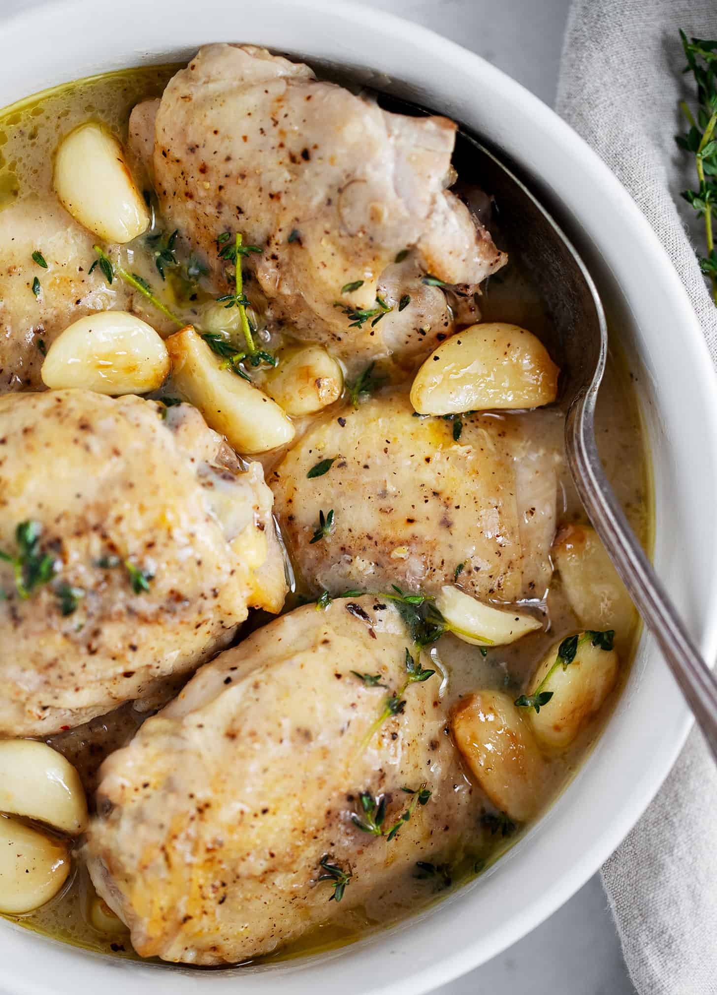 Rustic garlic chicken with gravy in bowl with spoon.