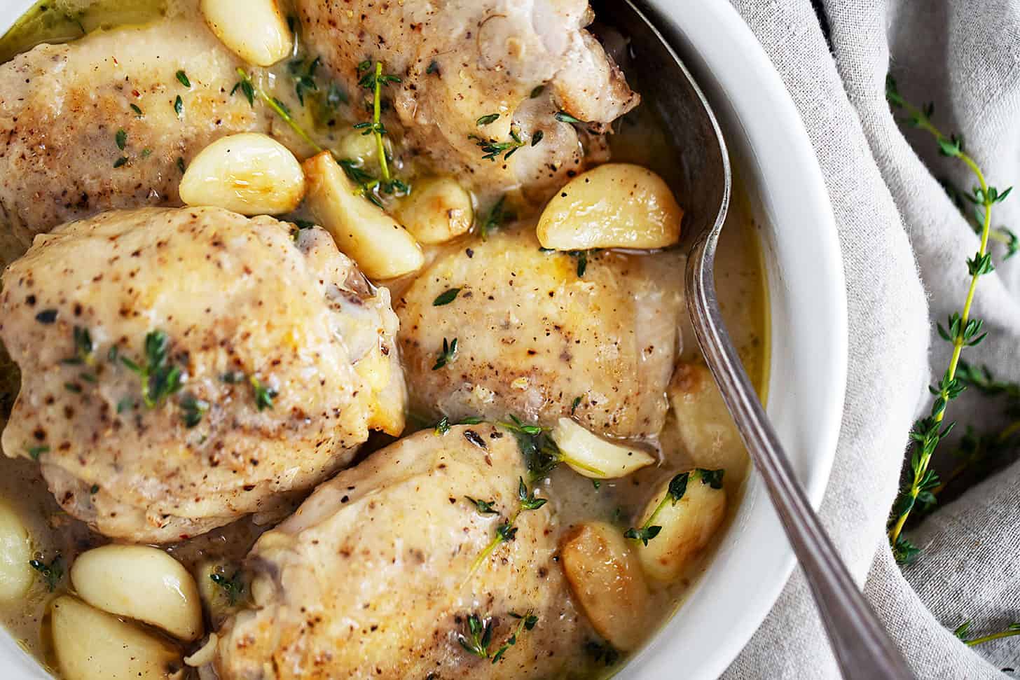 Rustic garlic chicken and gravy in bowl with spoon.