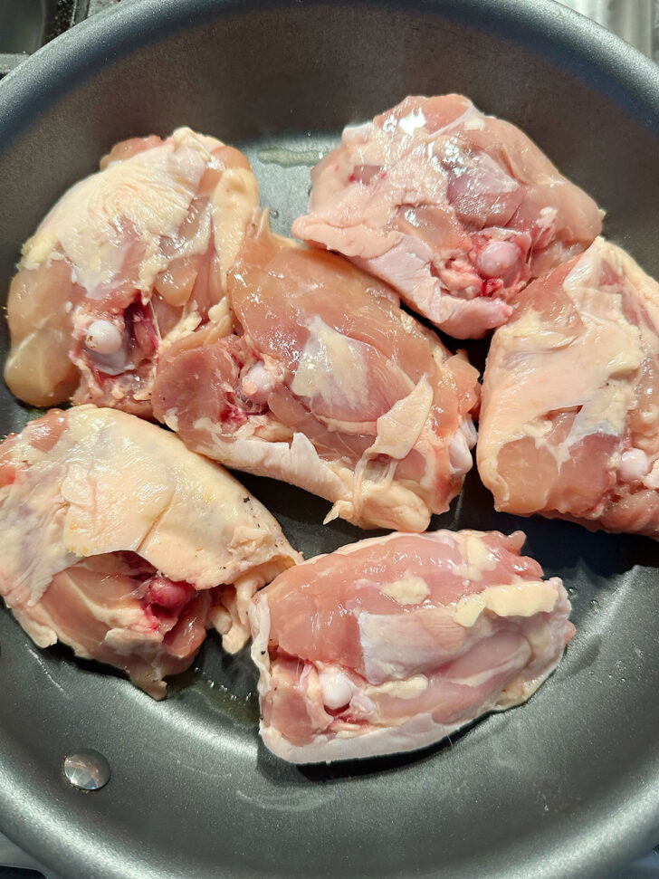 Chicken thighs placed into skillet.