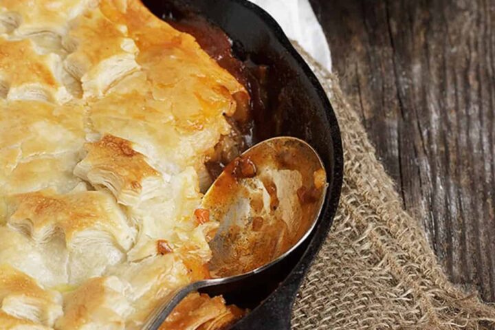 Beer-Braised beef and vegetable pie with puff pastry in skillet