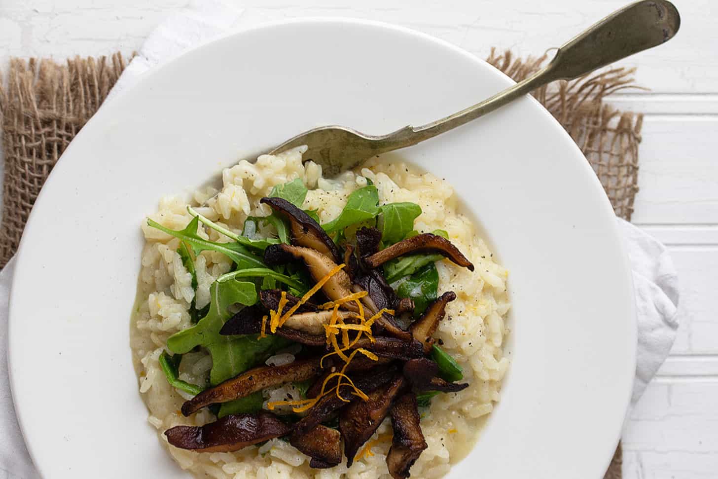 lemon risotto with shiitake mushrooms on top and arugula