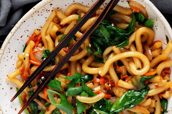 spicy udon noodles in bowl with chopsticks