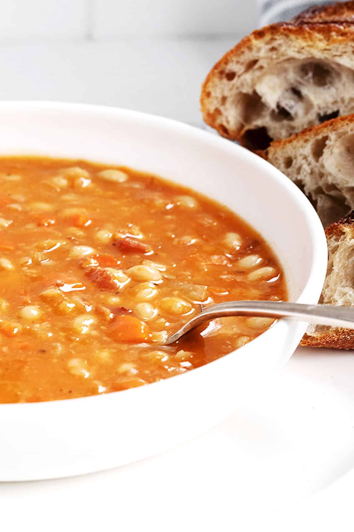 bean with bacon soup in white bowl with bread