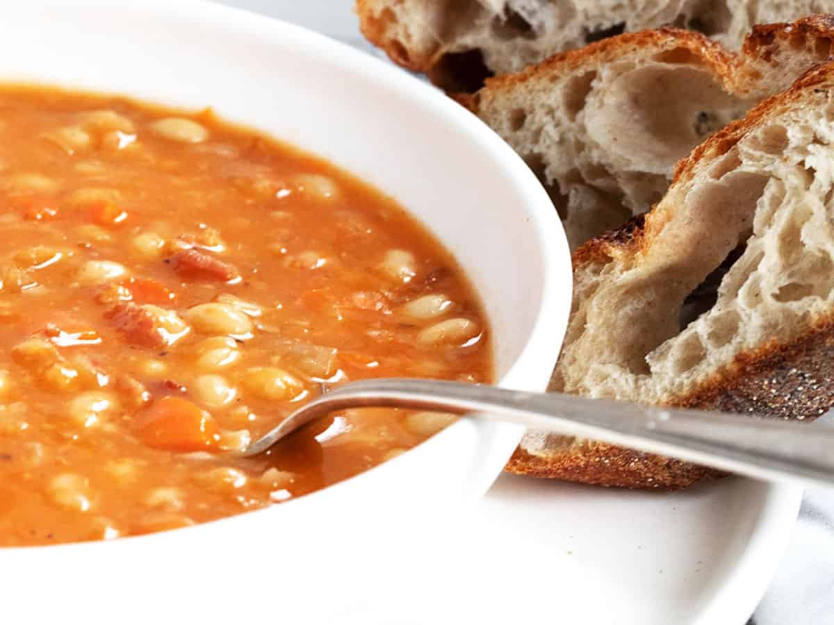 bean with bacon soup in bowl with bread on the side