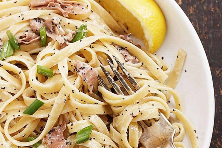 lemon poppy seed pasta with prosciutto on white plate