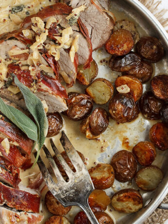 prosciutto wrapped pork tenderloin in pan with roasted potatoes and pan sauce