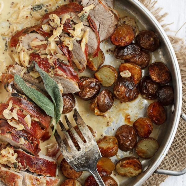 prosciutto wrapped pork tenderloin in pan with roasted potatoes and pan sauce