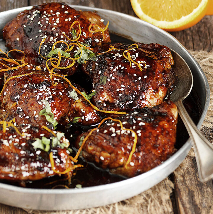 Asian sticky chicken in serving bowl with spoon