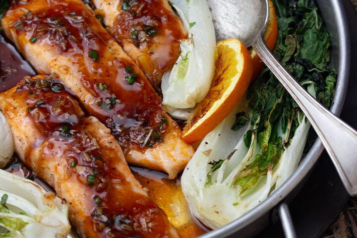 spicy orange salmon in baking dish with bok choy