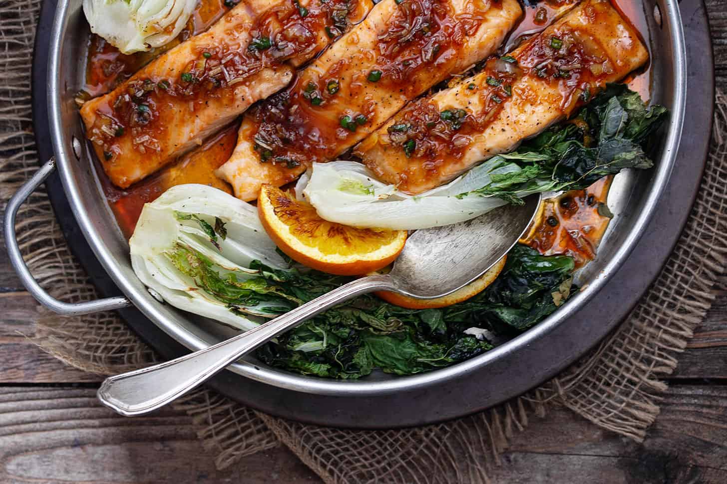 spicy orange salmon in baking dish with bok choy