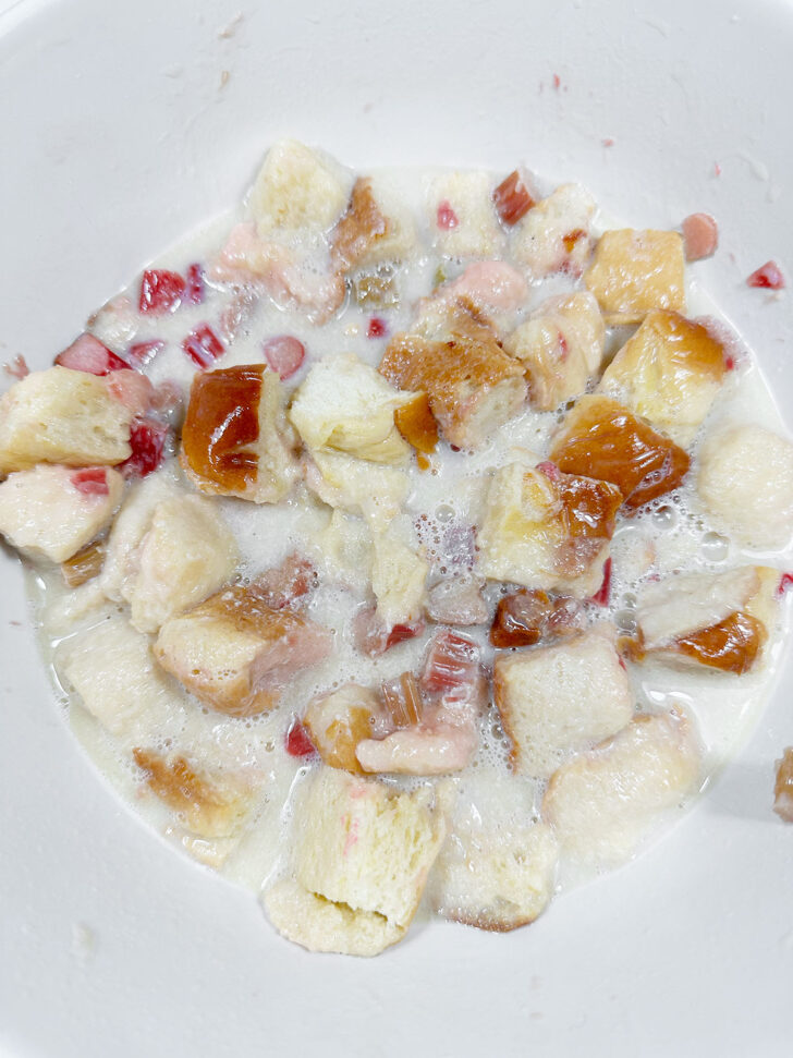 Warmed milk mixture added to bowl with bread and rhubarb.