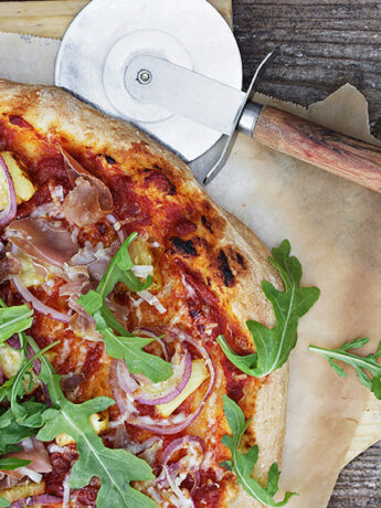 pineapple prosciutto pizza on pizza peel