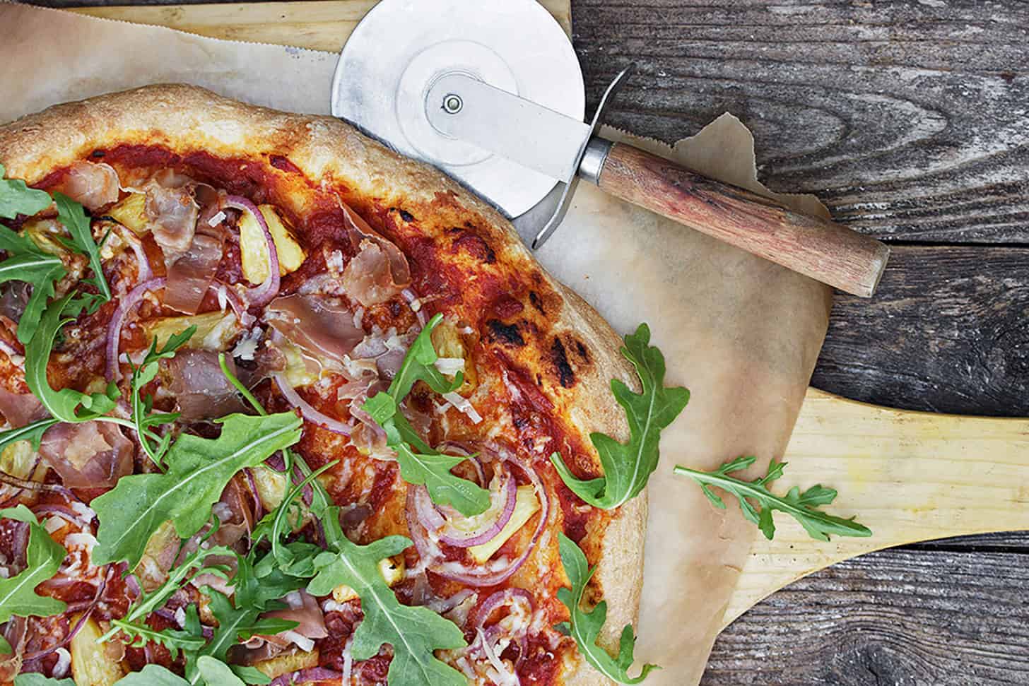 pineapple prosciutto pizza on pizza peel