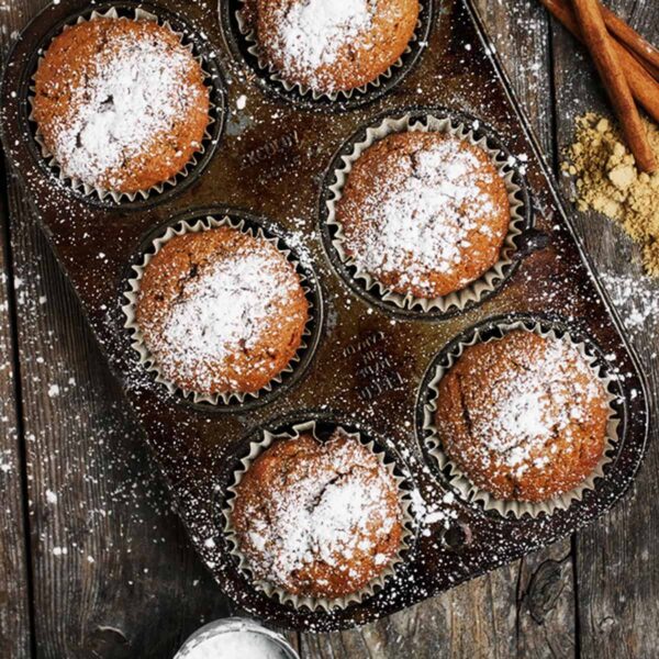 gingerbread muffins in muffin tin with powdered sugar on top