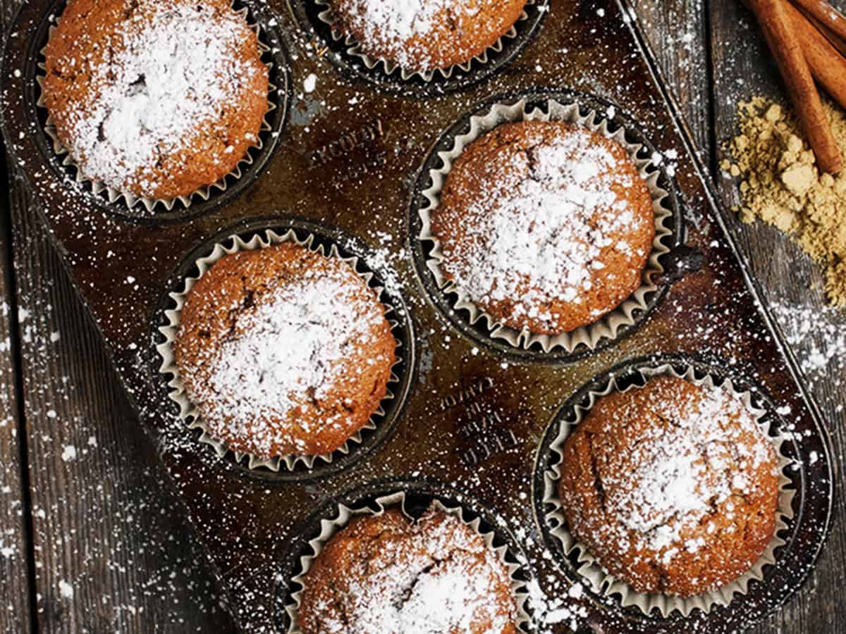 gingerbread muffins in muffin tin with powdered sugar on top