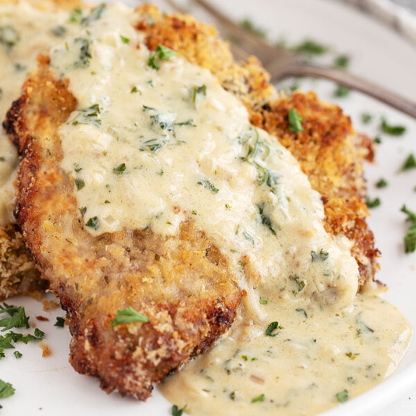 Oven-baked panko breaded pork chops on plate with mustard sauce.